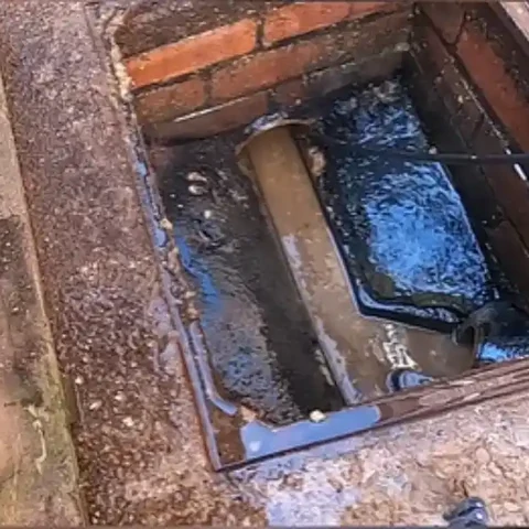 Brick-lined floor drain after cleaning with a water hose line in the drain